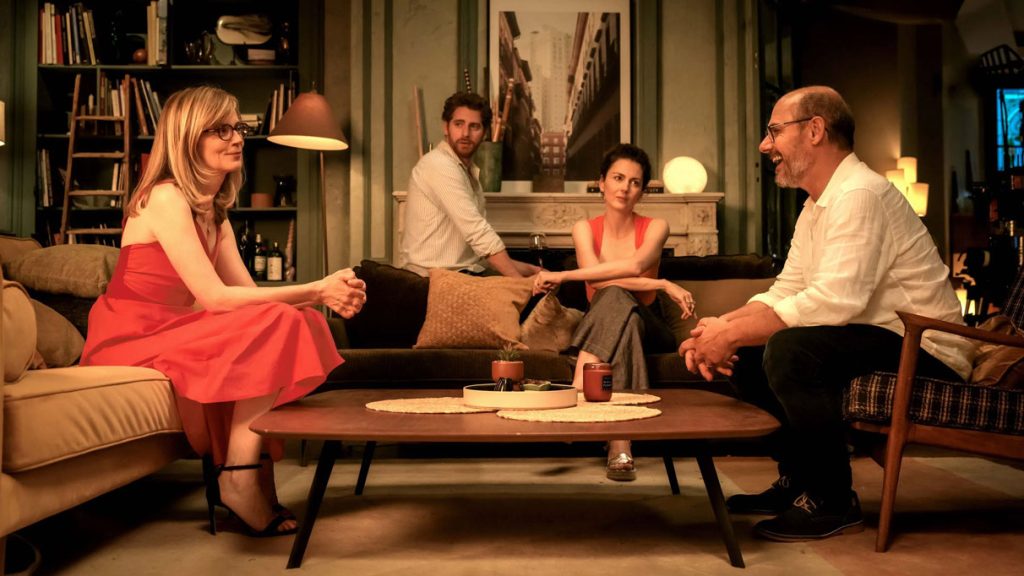 Scène de huis clos du film Et plus si affinités les deux couples discutent dans le salon de l'appartement parisien