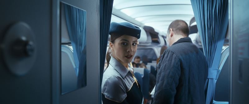 L'hôtesse jette un œil dans l'allée de l'avion, juste avant que tout bascule, dans 7500.